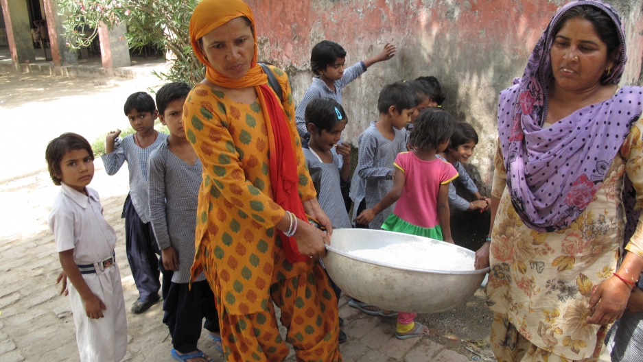 Saroj (left) and Santosh (right), carry a bowl of white rice after washing it. Saroj (left) and Santosh (right), carry a bowl of white rice after washing it.